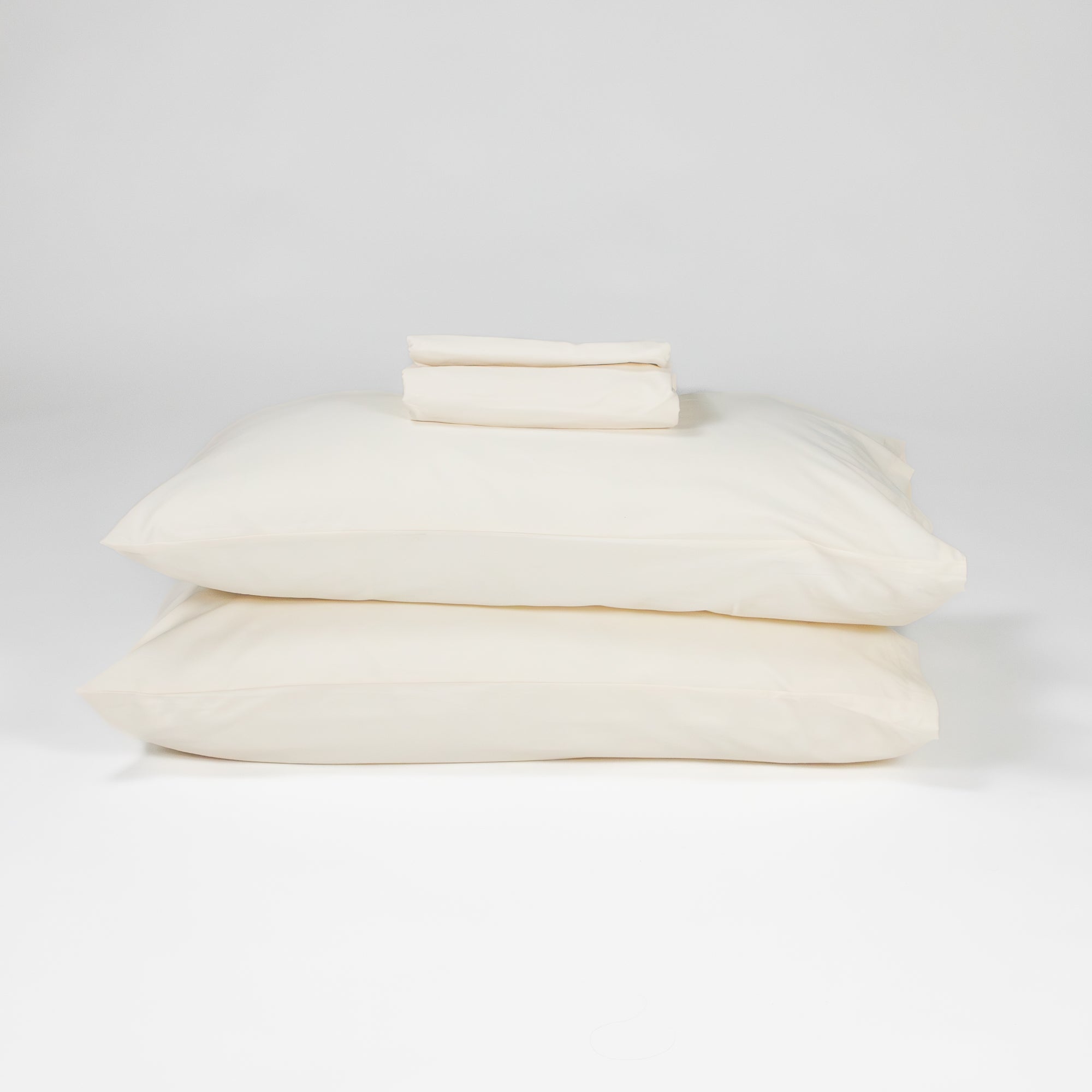 Fawcett Organic Cotton Bed Sheet Set stacked with pillows natural