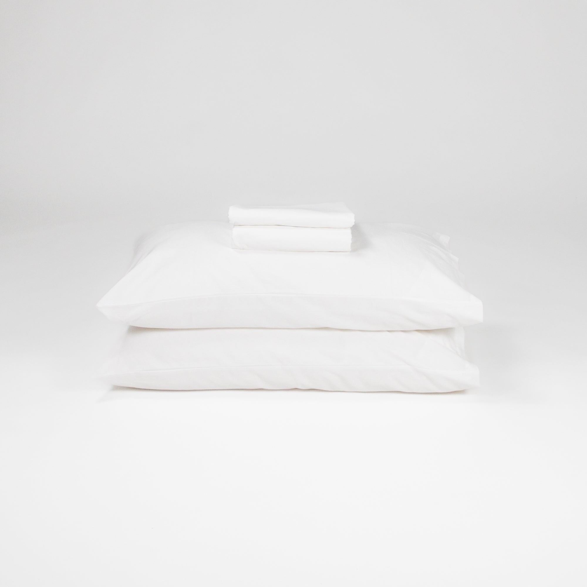 Fawcett Organic Cotton Bed Sheet Set stacked with pillows white