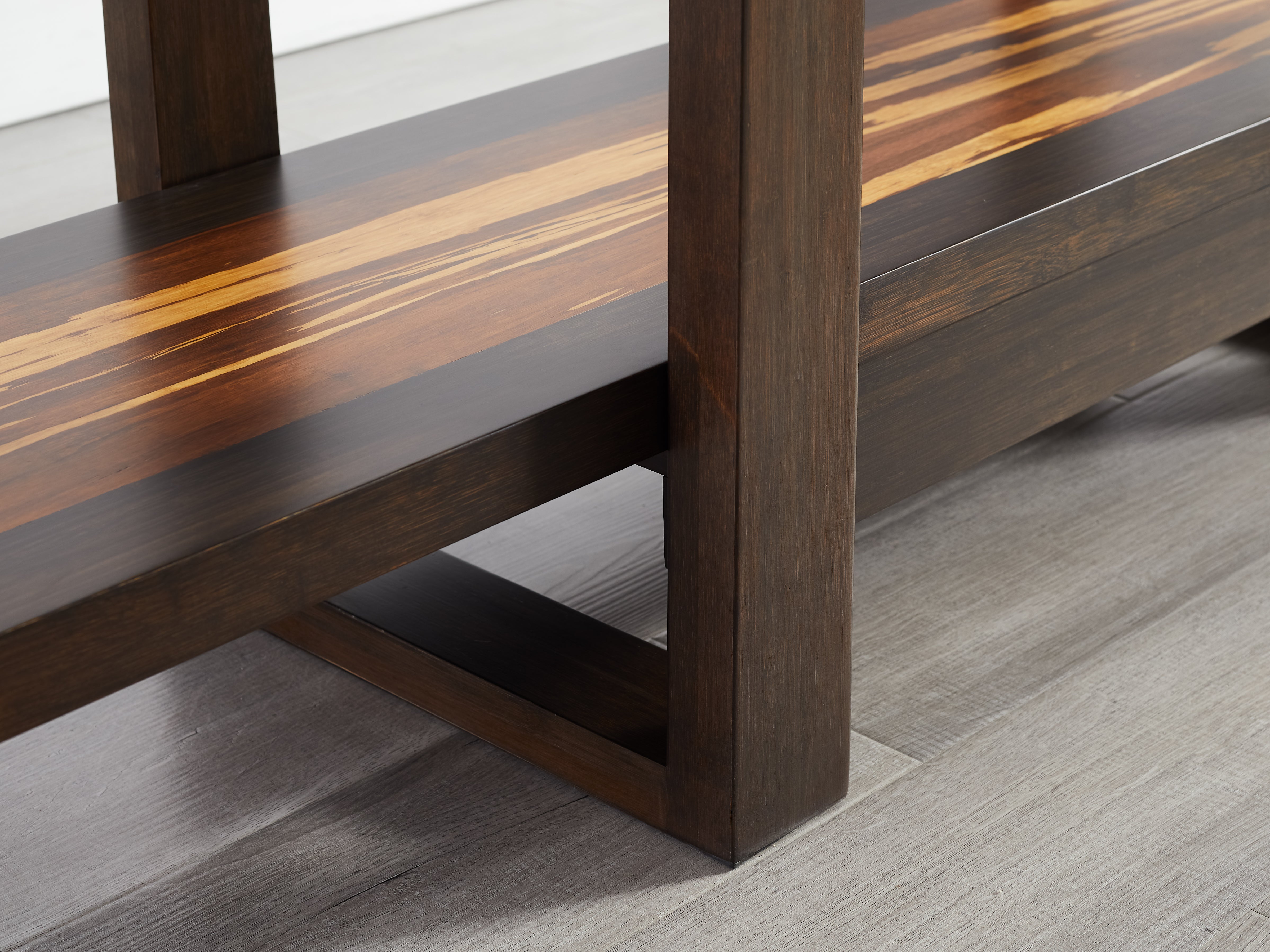 Close-up of a wooden book case with a reflective surface on a gray floor.