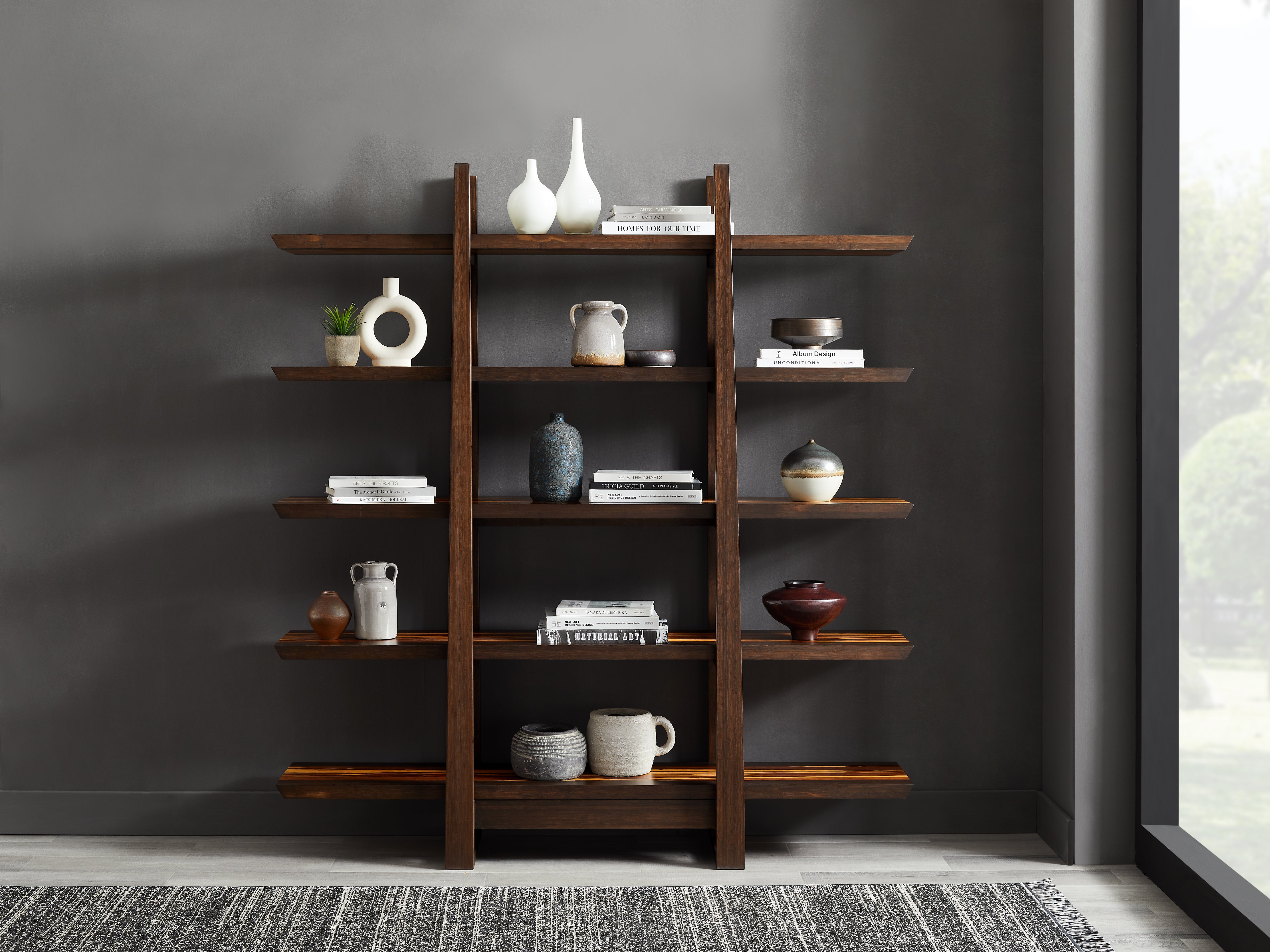 Wooden bookshelf with decorative items against a gray wall